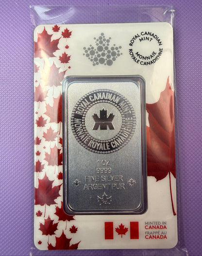A 1 oz silver bullion bar from the Royal Canadian Mint, presented in its original plastic packaging with a white and red maple leaf card backing, set against a purple textured background.
